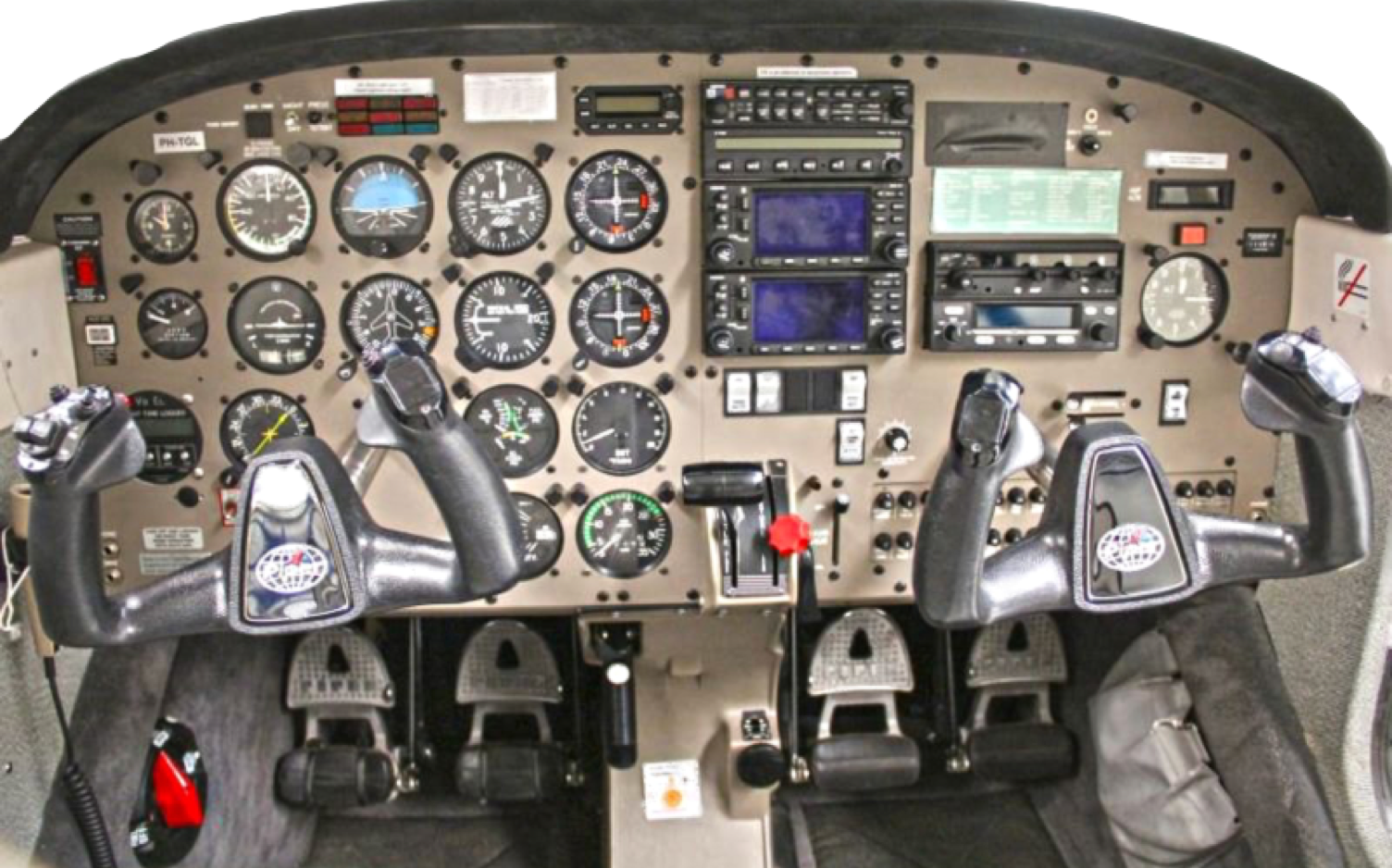 Cockpit van een klein vliegtuig met instrumentenpanelen, meters, knoppen en twee stuurwielen.